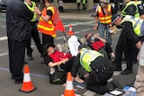 Police kneeling on the ground with a protester on the road