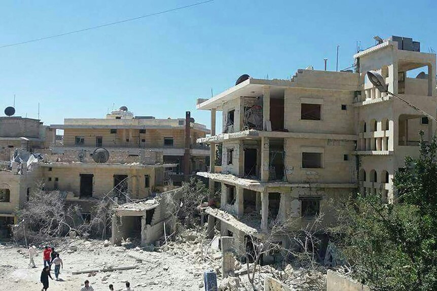 People gather in front of the damaged building of a maternity hospital supported by Save the Children in Syria.