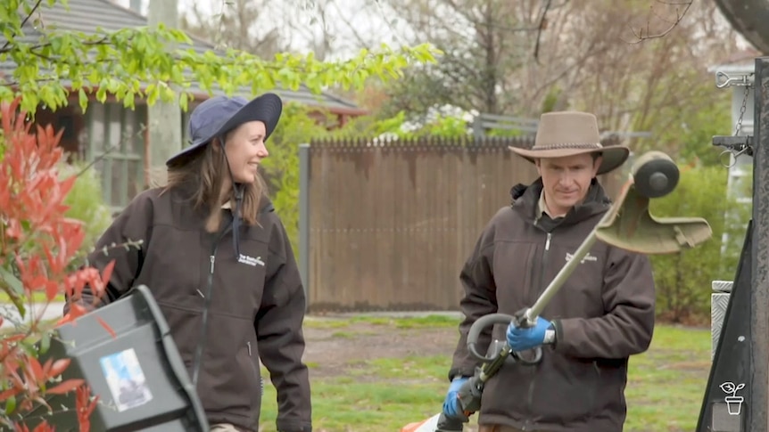 Two gardeners carrying gardening tools.