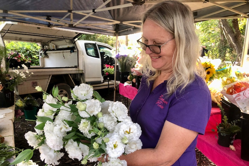 A woman looks down at a beautiful white bunch of lisianthus flowers