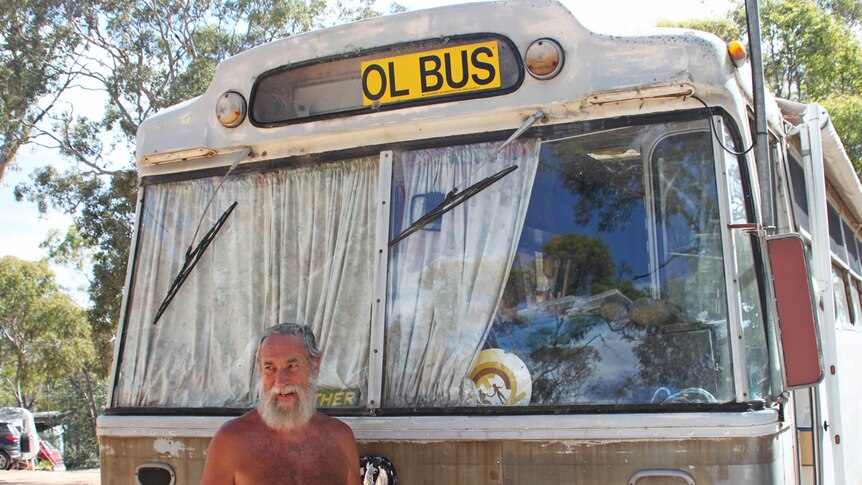 Man standing naked in front of a bus