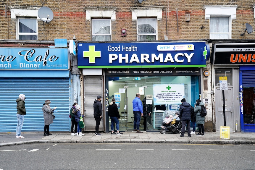 People wait in line outside a pharmacy in London