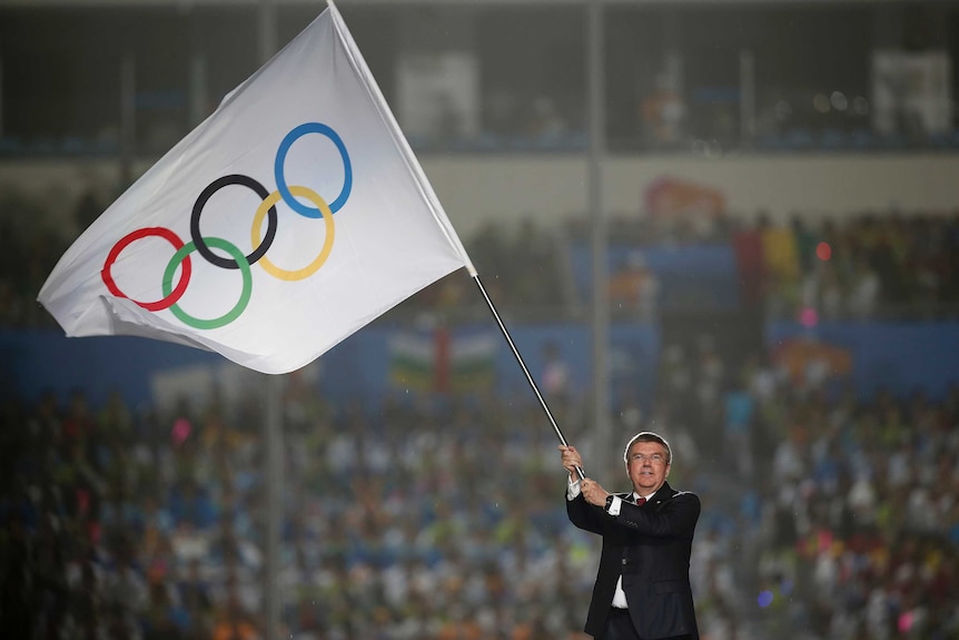 IOC chief Thomas Bach waves the Olympic flag during the closing ceremony of the 2014 Nanjing Youth Olympic Games