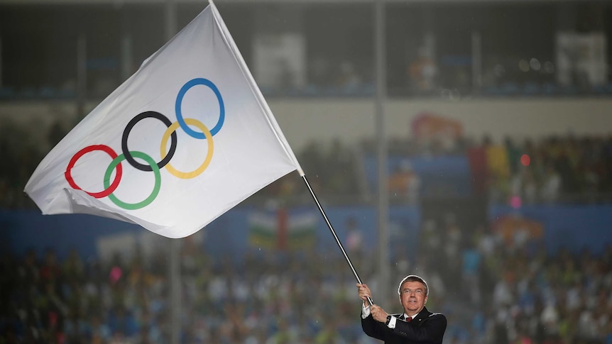IOC chief Thomas Bach waves the Olympic flag during the closing ceremony of the 2014 Nanjing Youth Olympic Games