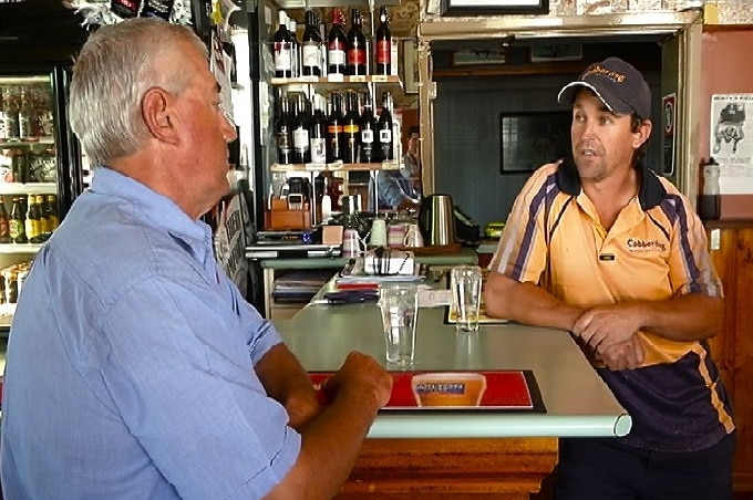 Tradesman sits at the bar with another man in a blue shirt
