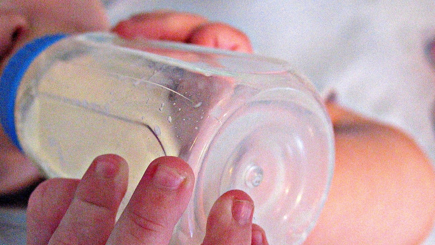 A baby drinks milk from a bottle.