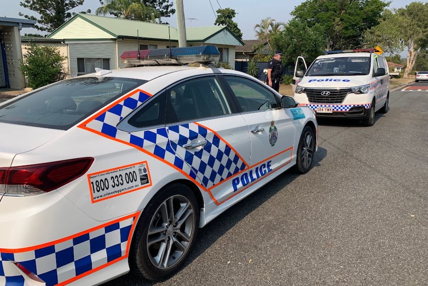 a police car and a police van parked in a suburban street