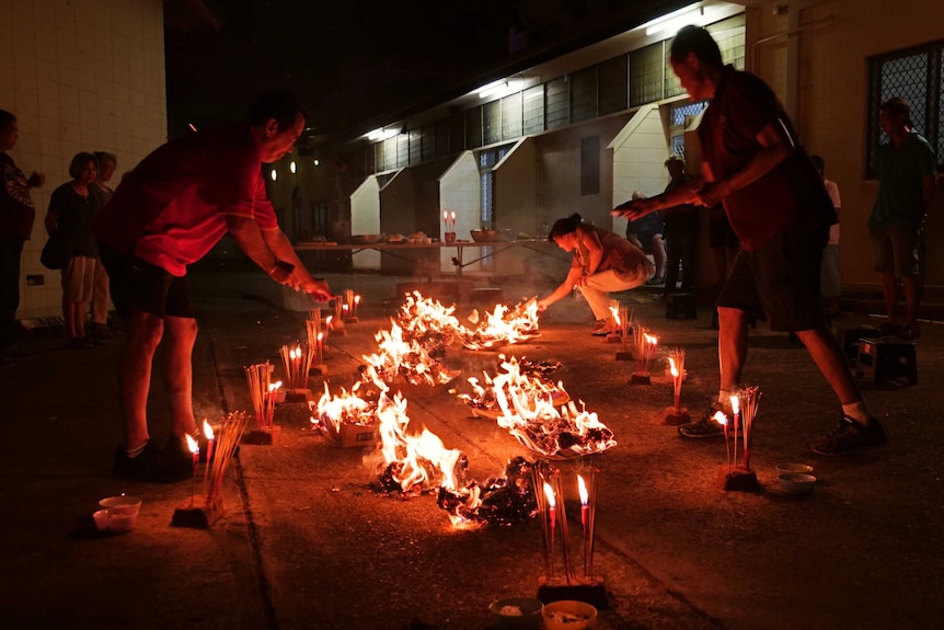 Chinese community lighting joss paper during ceremony.