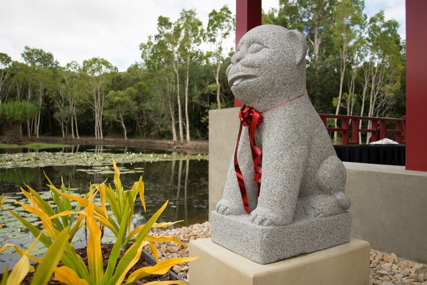 A stone 'heavenly dog' with a red ribbon around its neck guards the entrance to the friendship garden's pavilion.
