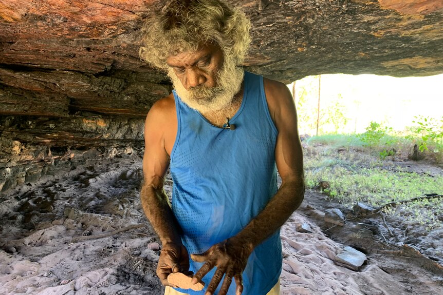 Jeffrey Lee holds a stone inside a rock structure in Kakadu.