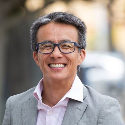 Huyen Tran wearing glasses and a wide smile looking at the camera