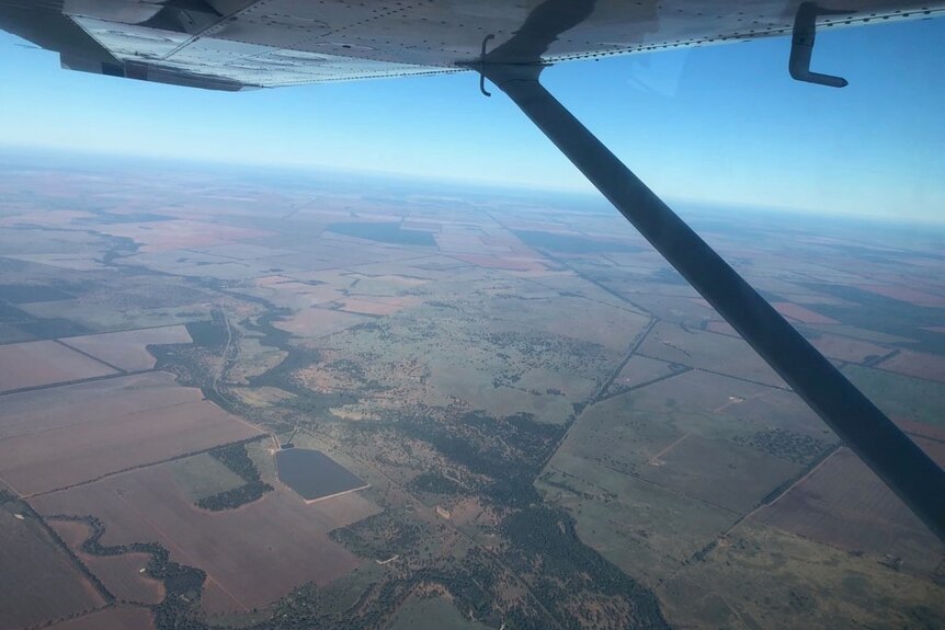 A view from the air of green and brown fields from a small aircraft.