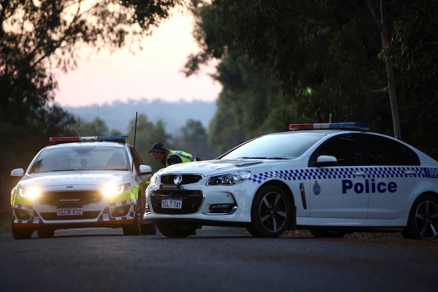 Police officers in a car stop to talk to another officer at a roadblock near the Osmington property.