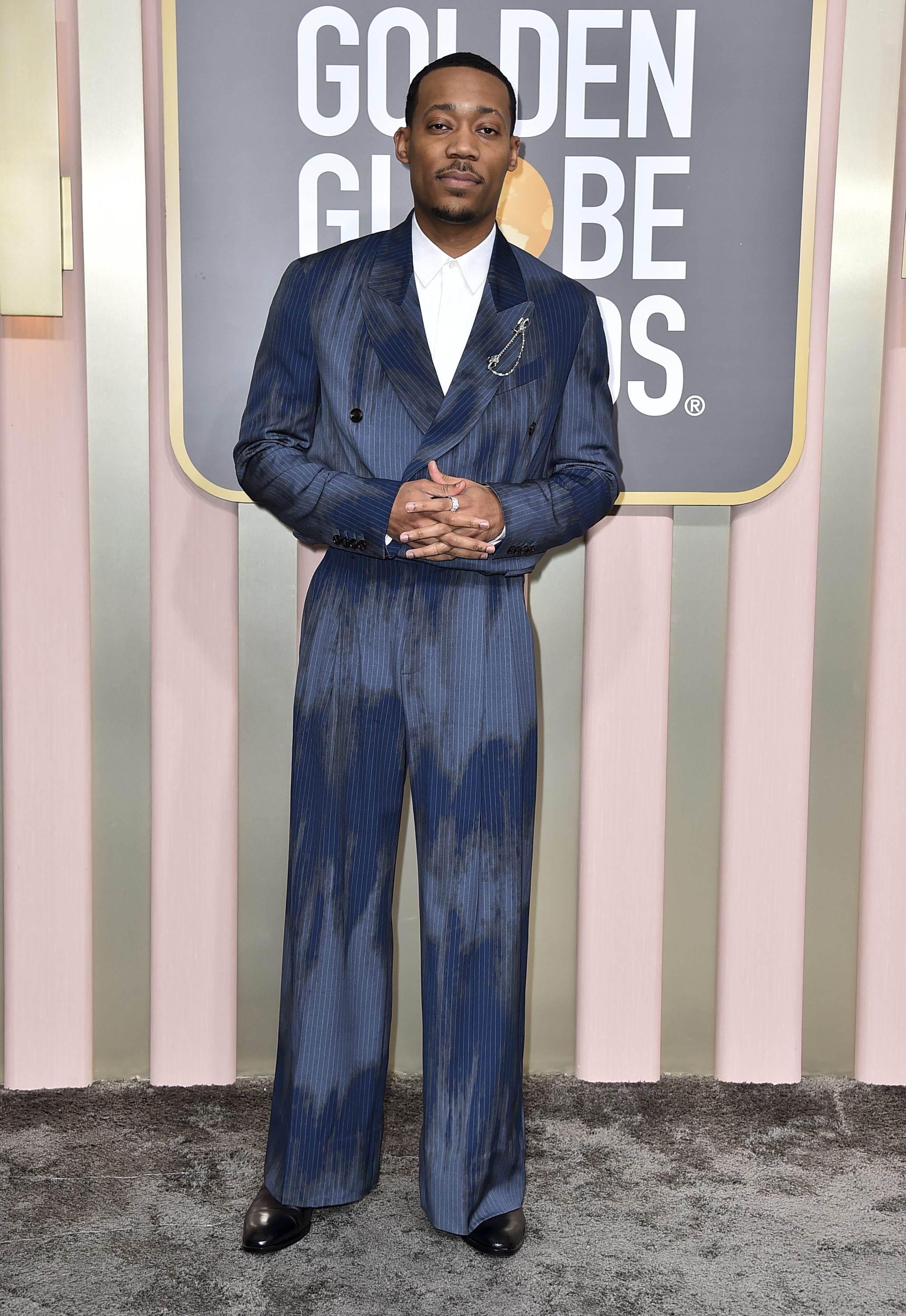 Tyler James Williams wearing a shiny dark blue suit with a white shirt.