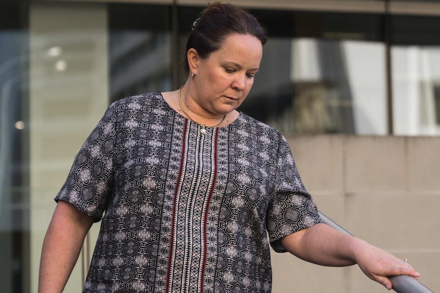 A woman in a patterned dress walks down steps in front of the Perth District Court.