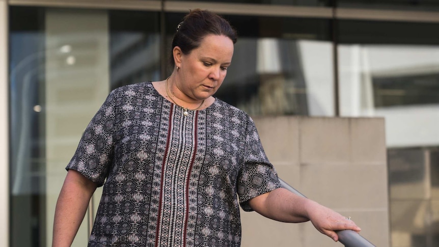 A woman in a patterned dress walks down steps in front of the Perth District Court.