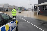 A police officer looks out at a flooded road.