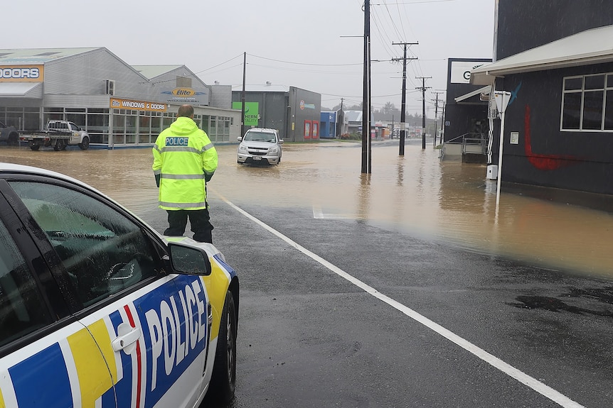A police officer looks out at a flooded road.