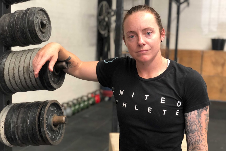 A woman leaning on a weights bench