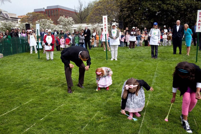 President Barack Obama cheers on a young child as she rolls her egg toward the finish line