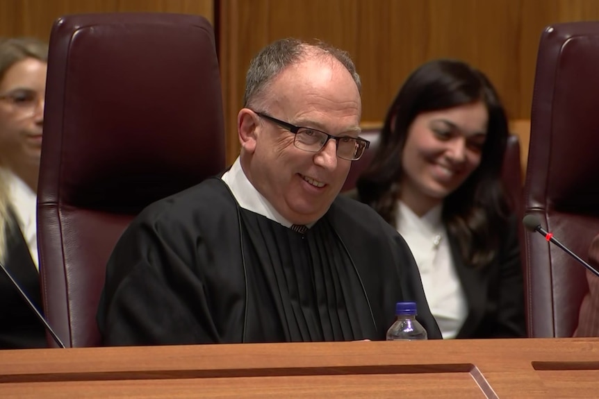 A man in judge's robes smiles.