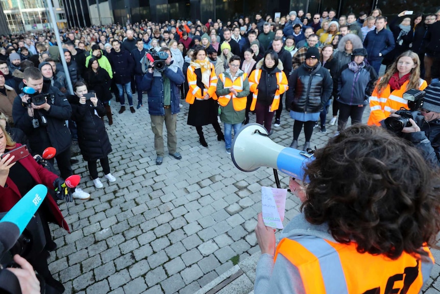 A woman holds a megaphone and speaks to hundreds of Google employees outside the company's Dublin office