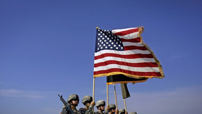 US soldiers carry an American flag as they unfurl their division's new colours