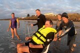 People in bathers laugh with Jim Pevitt as he is pushed into ocean
