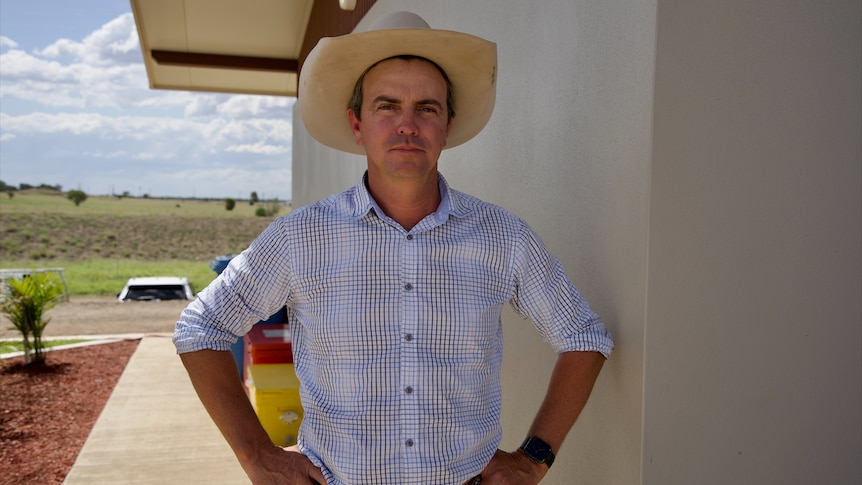 A man with a cowboy hat staring down the camera with a neutral expression