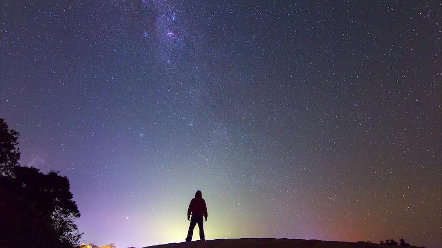 Dylan O'Donnell standing on rock in front of sky full of stars.