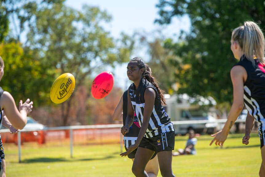 An Indigenous woman handballs a football