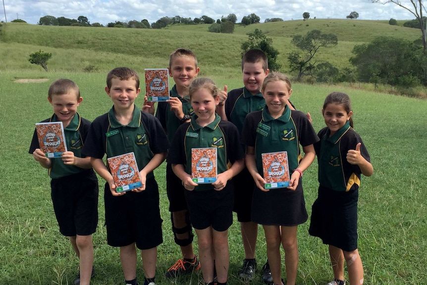 seven school children stand outside their school with copies of their DVD