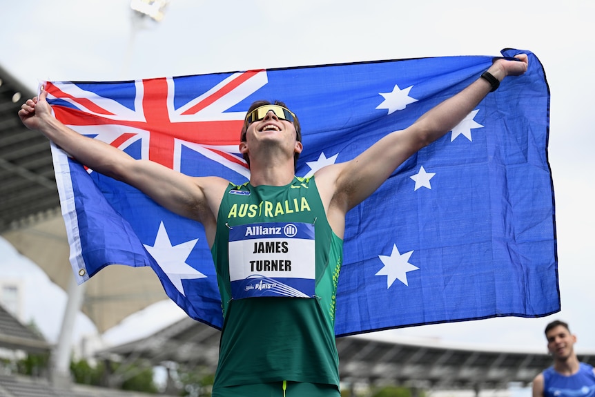 James Turner holds up the Australian flag behind his head at the Para-athletics world championships.