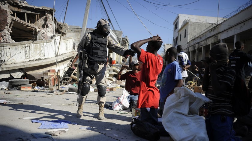 A Haitian policeman arrests looters in a street of Port-au-Prince