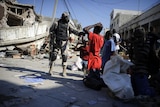 A Haitian policeman arrests looters in a street of Port-au-Prince