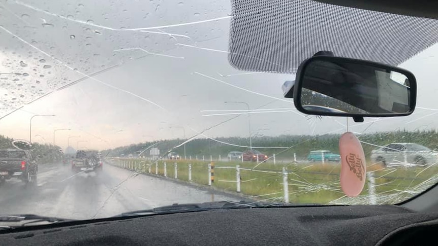 Many cracks on the glass of a wet car windscreen, shown from the perspective of the car passenger
