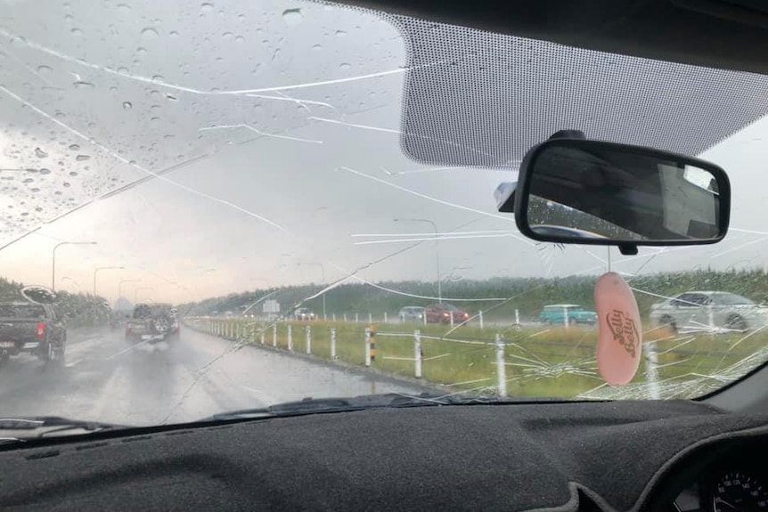 Many cracks on the glass of a wet car windscreen, shown from the perspective of the car passenger