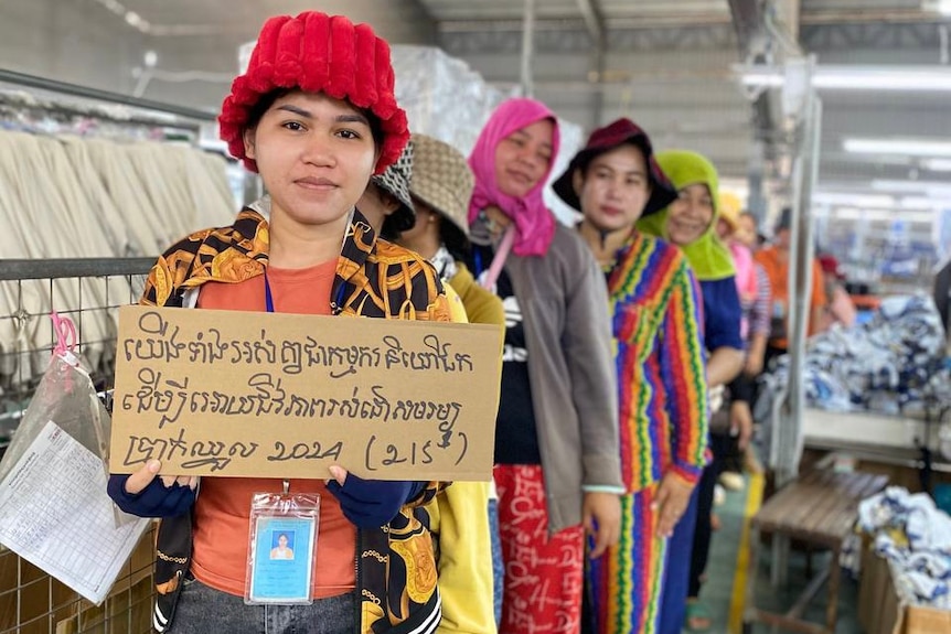 Garment worker at unnamed factory holding sign saying: "We are workers to have a decent living wage 2024".