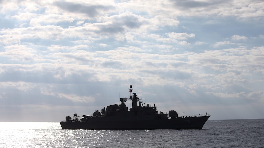 A large warship sits on the ocean.