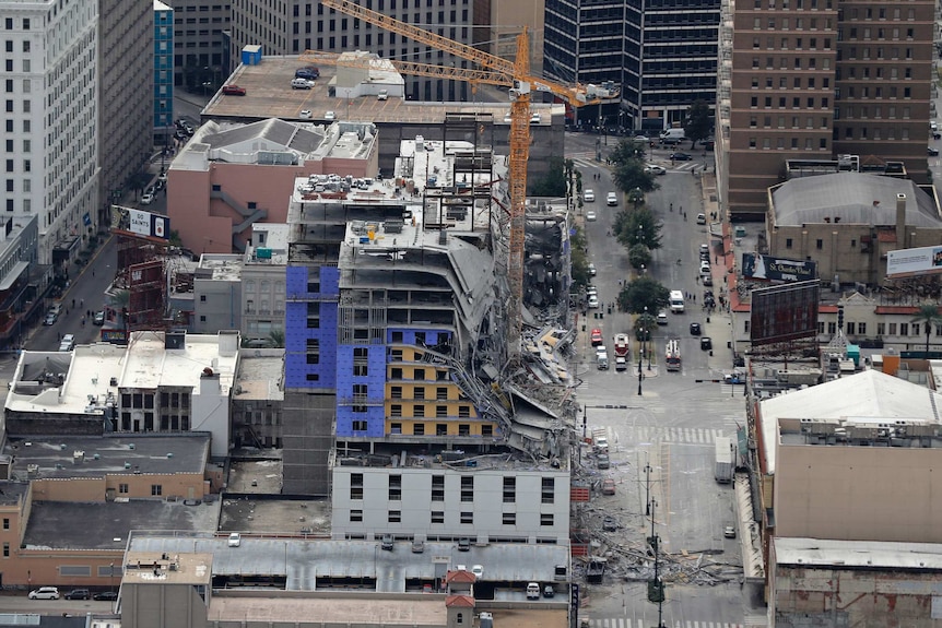 This aerial photo shows a building after a fatal partial collapse with a crane next to it there is also debris on the road below