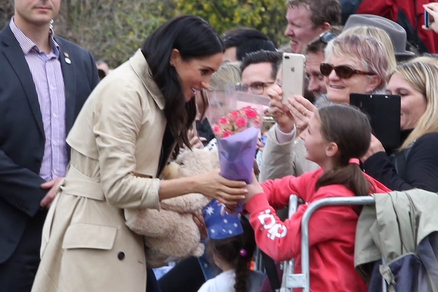 The Duchess of Sussex takes a bunch of flowers from a young girl.