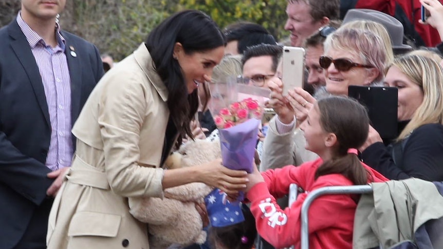The Duchess of Sussex takes a bunch of flowers from a young girl.