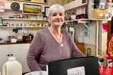 Woman standing behind cash register smiling at camera 