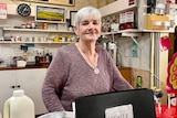 Woman standing behind cash register smiling at camera 