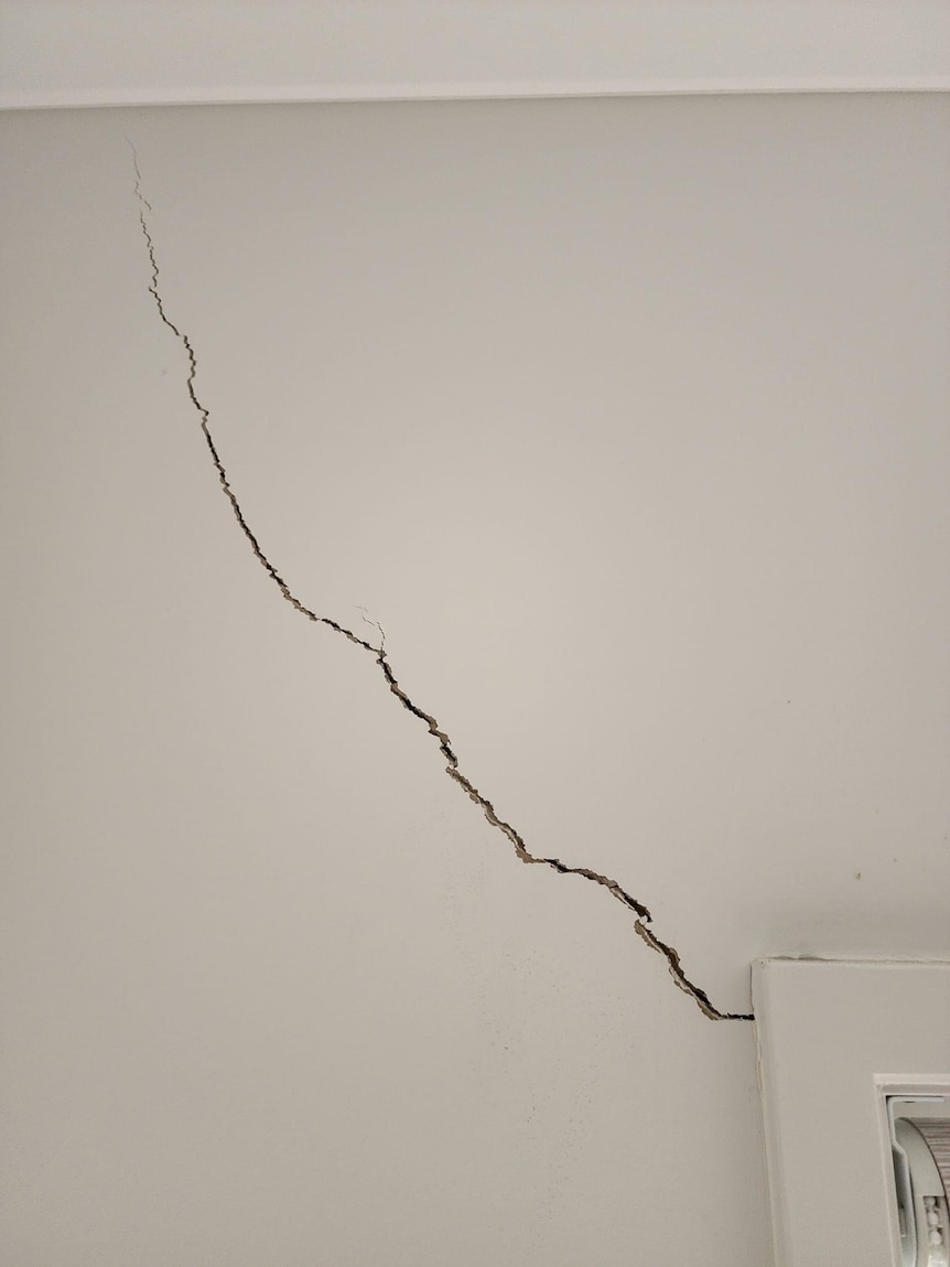 A large crack creeping up from a door frame.