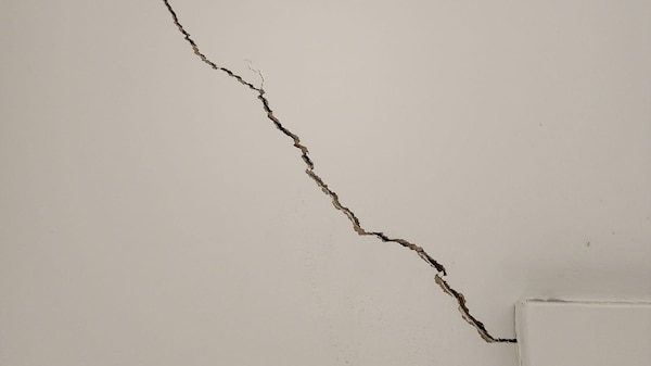 A large crack creeping up from a door frame.