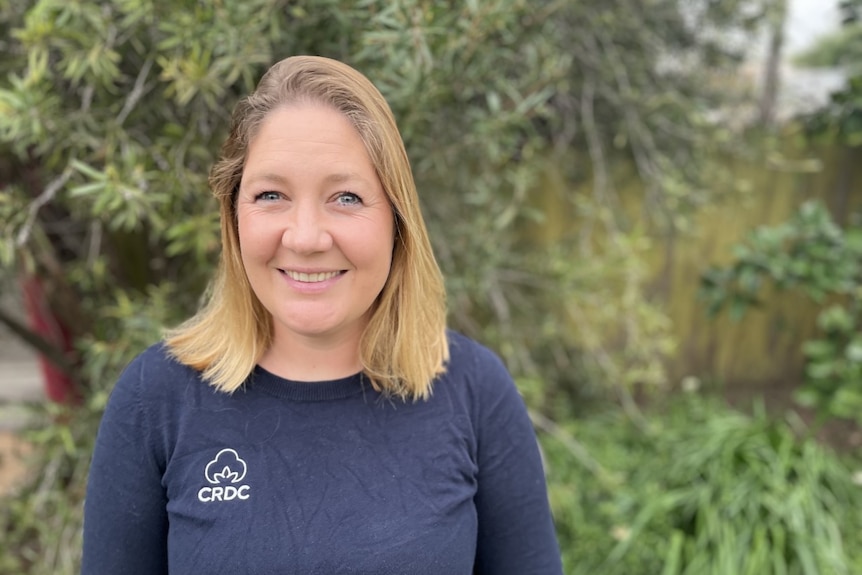 A woman, wearing a blue cotton T-shirt, stands in a garden.