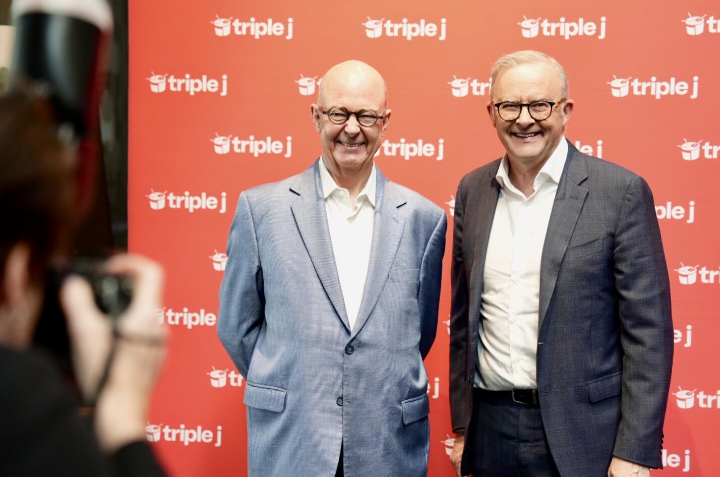 Two men in suits smile at the camera.