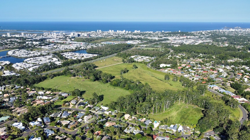 An aerial view showing farmland and all of the development around it with the ocean in the background.