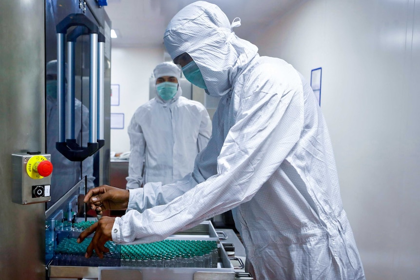 Two men in full PPE looking at a machine